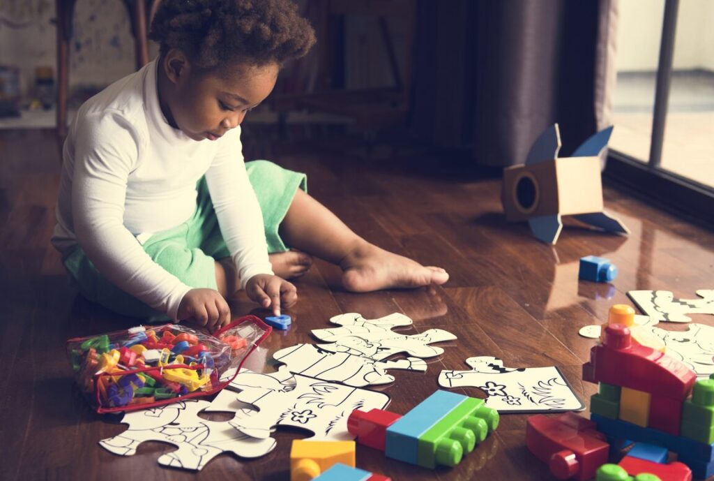 african descent kid enjoying puzzles on wooden floor